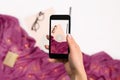 Female hand with a smartphone makes a photo workspace with notebook, coffee cup, scarf, glasses. Royalty Free Stock Photo