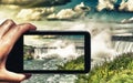 Female hand with smartphone taking a picture of Niagara Falls. Tourism concept Royalty Free Stock Photo