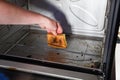 Female hand with sponge and detergent cleaning the kitchen oven from burnt drops Royalty Free Stock Photo