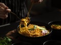 Female hand with spoon and fork ready to eat Noodles curry soup with Chicken Khao Soi