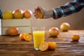 Female hand squeezing fresh orange to the glass on wood table Royalty Free Stock Photo