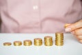 Female hand stacking gold coins into increasing columns