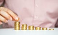 Female hand stacking gold coins into increasing columns