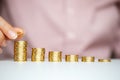 Female hand stacking gold coins into increasing columns