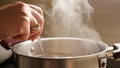 Female hand stirring boiling soup in pot. Healthy nutrition, cooking at home, hot steam