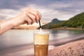 Female hand stirring a straw on a greek cold coffee, freddo cappuccino, outdoors Royalty Free Stock Photo