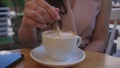 female hand stirs sugar in a cup of fresh coffee