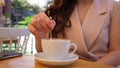 female hand stirs sugar in a cup of fresh coffee