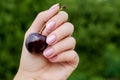 Female hand with summer nail design. Glitter pink nail polish manicure with gems nail art. Female hand hold red cherry Royalty Free Stock Photo