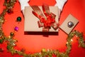 Female hand in sweater holding a red present box for Christmas, New Year, Valentine`a day on red background, top view