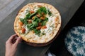 Female hand take a piece of Fresh italian pizza with tomatoes, cheese, basil on black stone table. Copy space. Homemade Royalty Free Stock Photo