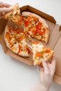 Female hand take piece of mexican pizza in cardboard box for delivery on white solid background