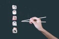 Female hand takes chopsticks sushi rolls with Chinese chopsticks. Lying on a black wooden board. View from above Royalty Free Stock Photo