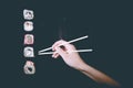 Female hand takes chopsticks sushi rolls with Chinese chopsticks. Lying on a black wooden board. View from above Royalty Free Stock Photo