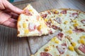 Female hand takes a slice of Pizza with Mozzarella cheese, ham and pineapple. Italian pizza on wooden table background Royalty Free Stock Photo