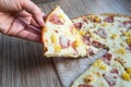 Female hand takes a slice of Pizza with Mozzarella cheese, ham and pineapple. Italian pizza on wooden table background Royalty Free Stock Photo