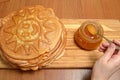 Female hand takes spoon honey from glass jar and puts on pancakes