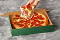 Female hand taking slice of pizza with melted mozzarella, pepperoni and jalapeno from carton box Royalty Free Stock Photo