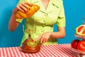 Female hand tasting crispy croissant on plaid tablecloth isolated on bright blue background. Vintage, retro style