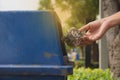 Female hand throwing crumpled paper into plastic trashcan.