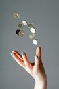 Female hand throwing money, one euro coins into air on gray background. Levitating cash. Copy space, vertical