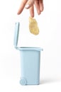 Female hand throws organic trash, potato stub into trash can, white background Royalty Free Stock Photo