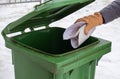 A female hand throws paper trash into a plastic container. The concept of sorting garbage, waste, for further processing Royalty Free Stock Photo