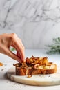 Female hand and toast with fried chanterelles and cheese, on marble background. Roasted wild mushrooms. Generative AI