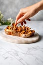 Female hand and toast with fried chanterelles, on marble countertop. Roasted wild mushrooms on a slice of bread. Generative AI