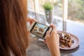 The female hand took a photo of the chocolate-covered waffles in the coffee shop and prepared to upload to a social app