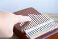 Female hand touches metal plates of kalimba, African percussion musical instrument class lamellaphones or plucked reed idiophones Royalty Free Stock Photo