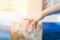 Female hand touches the spray of the fountain. Woman`s hand in the fountain