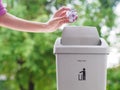 female hand trowing a paper into a garbage bin on bokeh background. cleaning concept. Royalty Free Stock Photo