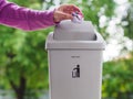 female hand trowing a paper into a garbage bin on bokeh background. cleaning concept. Royalty Free Stock Photo