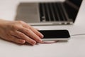 Female hand tup phone on wireless charging. Work place near at the laptop. Top view Royalty Free Stock Photo