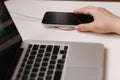 Female hand tup phone on wireless charging. Work place near at the laptop. Top view Royalty Free Stock Photo