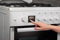 Female hand turning on white kitchen gas stove on gray Royalty Free Stock Photo