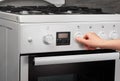 Female hand turning on white kitchen gas stove on gray Royalty Free Stock Photo