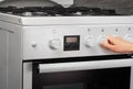 Female hand turning on white kitchen gas stove on gray Royalty Free Stock Photo