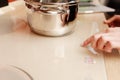 Female hand turns on electric hob closeup, finger presses sensor button on modern white induction cooker. Metal steel Royalty Free Stock Photo