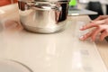 Female hand turns on electric hob closeup, finger presses sensor button on modern white induction cooker. Metal steel Royalty Free Stock Photo