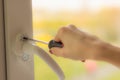 Female hand twists the on the window with a screwdriver, close-up