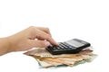 Female hand is typing on a calculator against the background of a heap of euro banknotes / isolated on white.