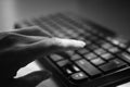 Female hand is typing on the keyboard, selective focus on the finger, black and white photo Royalty Free Stock Photo