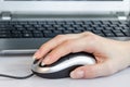 Female hand using computer mouse in front of laptop Royalty Free Stock Photo