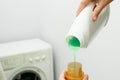 Female hand using or filling detergent in the washing machine. Pour green washing liquid, wash machine blured in background. Royalty Free Stock Photo