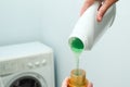 Female hand using or filling detergent in the washing machine. Pour green washing liquid, wash machine blured in background. Royalty Free Stock Photo