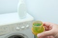 Female hand using or filling detergent in the washing machine. Pour green washing liquid, wash machine blured in background. Royalty Free Stock Photo