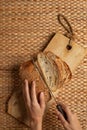 Female hand using long knife cutting bread on wood block showing air flour texture.