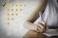 Female hand using a pen to fill out a questionnaire. Customer satisfaction questionnaire. Five star rating. Check the box for five